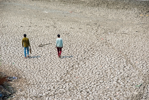 Cracked earth with two people walking across it