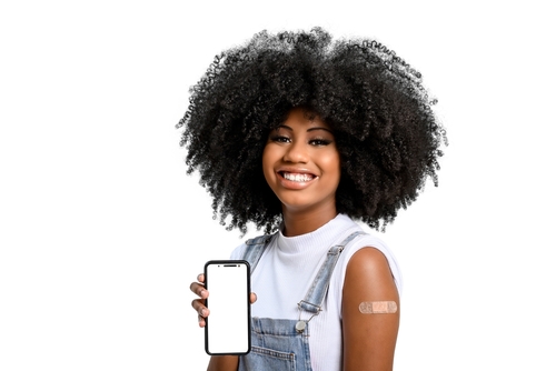 Teen woman with cell phone and evidence of recently having had a vaccine with a bandaid on her arm.