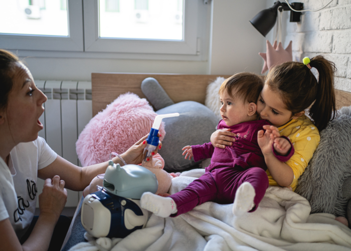 Women teaching two children to use a nebulizer