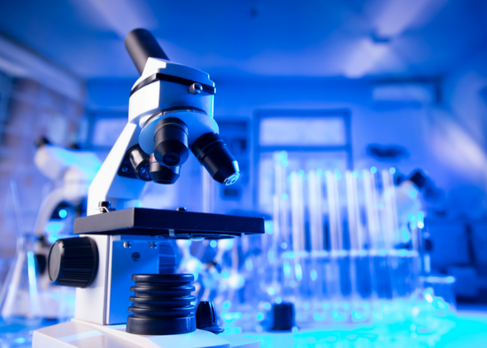 A microscope in a laboratory with test tubes in the background